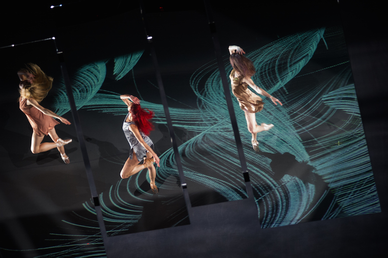 A view of the mirrored projection in Islands of Memories. We see the top of three women's heads. Their long hair flies as they spin on pointe.